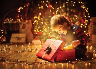 Christmas Child Open Present Gift, Happy Baby Boy looking to Magic Light in Box, Kid sitting front of Xmas Tree