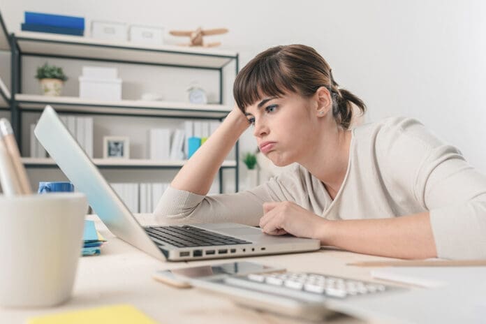 Tired disappointed woman working at office desk with a laptop, connection and computer problems concept