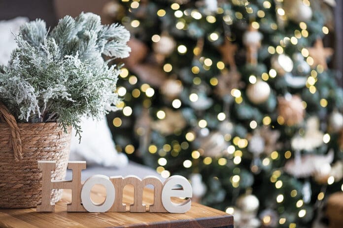 Beautiful holiday card. The concept of a happy new year and Christmas 2024. Christmas trees and a home sign on a wooden table in a cozy living room.