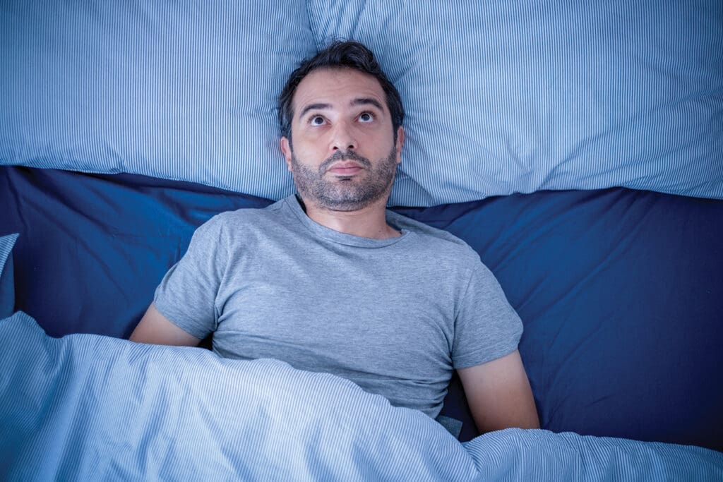 Anxious man trying to sleep but suffering insomnia