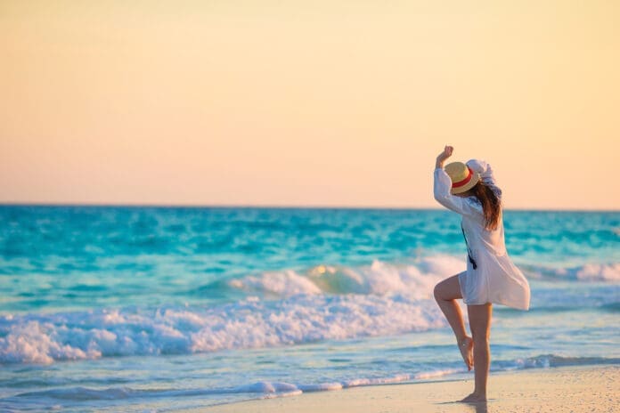 Young happy woman in swimsuit on white beach