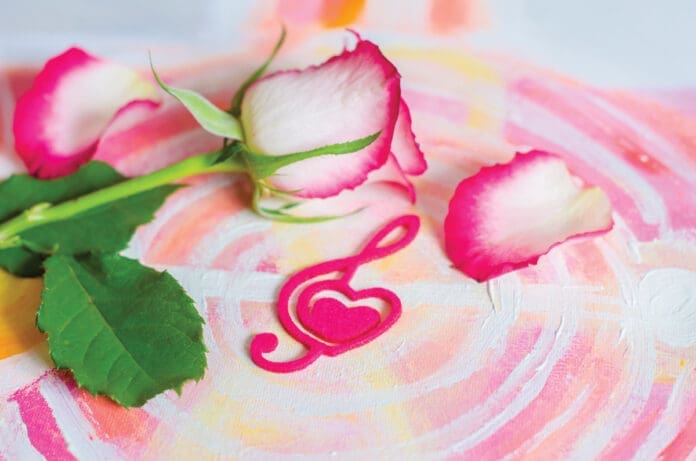 Rose with a decorative heart in the shape of a treble clef with pink felt on the background of painting. Valentine's day, mother's day congratulation.