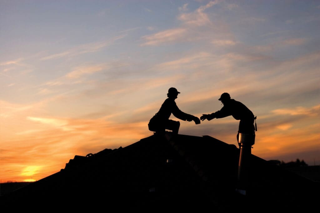 Two roofers working late on a roof top