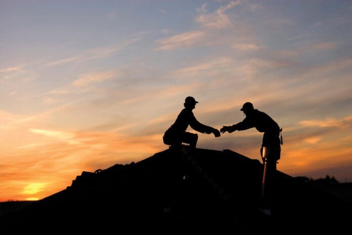Two roofers working late on a roof top