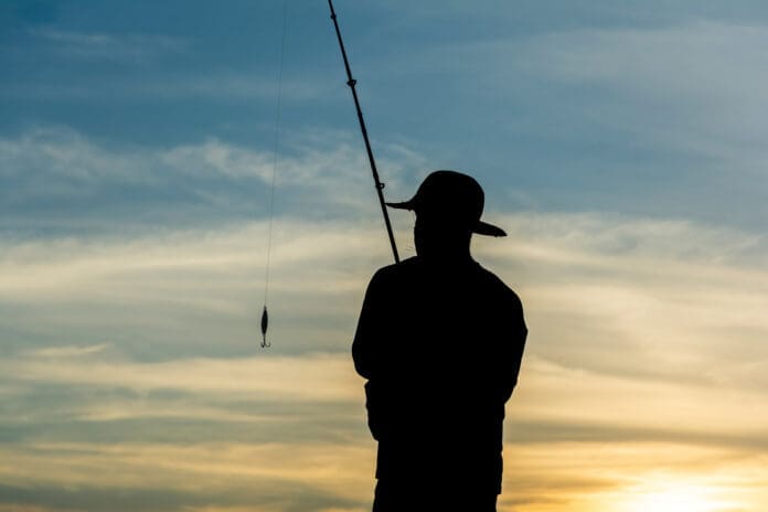 Silhouette of fishermen with their fishing rods on the rocks in search of fish.