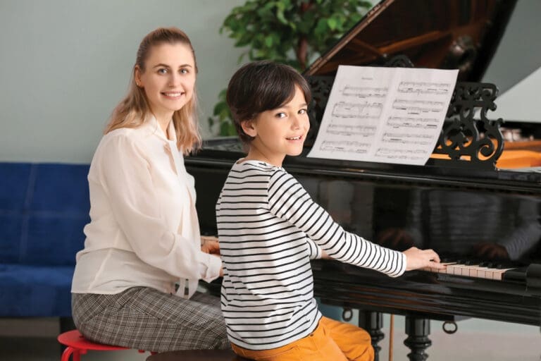 Private music teacher giving piano lessons to little boy