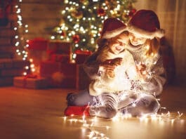 Merry Christmas! mother and child daughter with glowing garland near tree