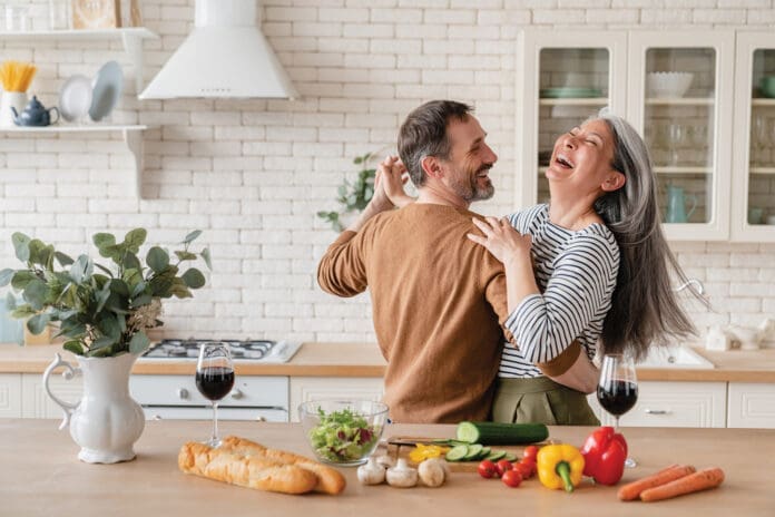 Happy cheerful middle-aged mature couple family parents dancing together in the kitchen, preparing cooking food meal for romantic dinner, spending time together. Active seniors Happy cheerful middle-aged mature couple family parents dancing together in the kitchen, preparing cooking food meal for romantic dinner, spending time together. Active seniors