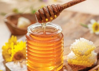 Natural organic honey in glass jar, honey dipper and honeycombs are near. Natural food background.
